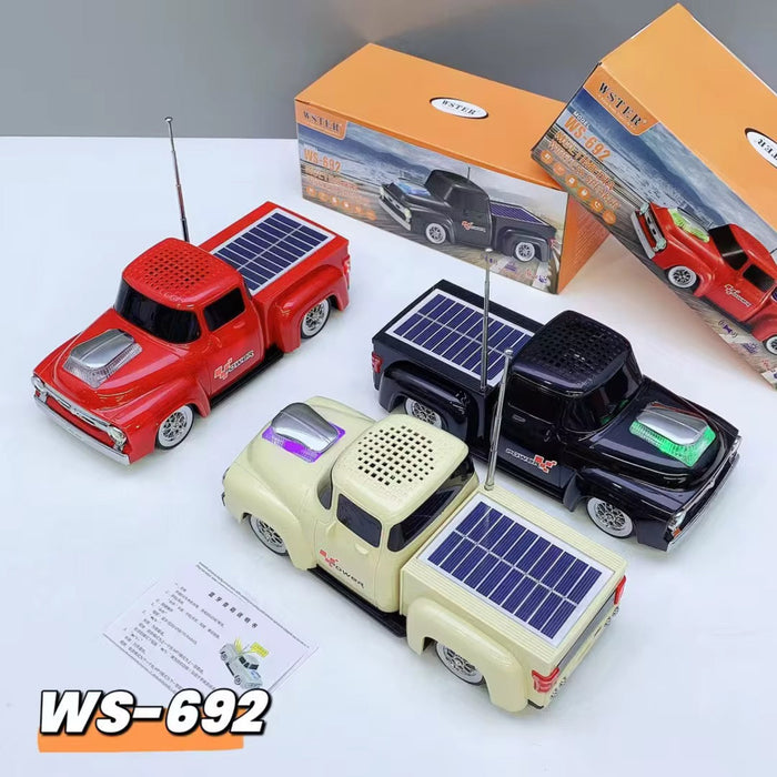 Three toy trucks with solar panels on a white surface, with packaging and a product sheet in the background.