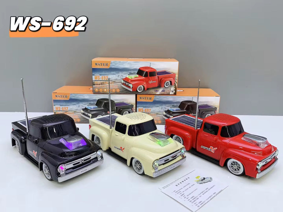 Three toy trucks in black, white, and red with a box in the background on a light gray surface.