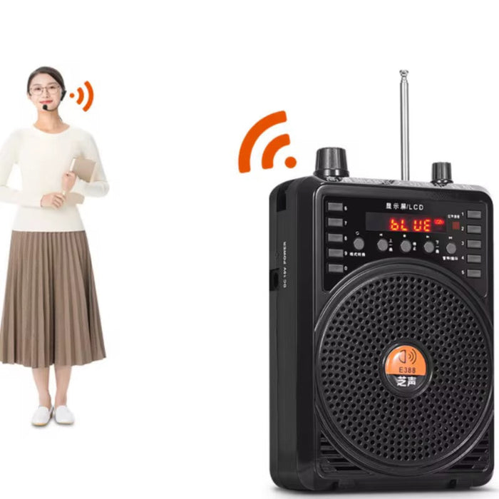 Black portable radio with digital display and antenna, standing next to a person holding a book.
