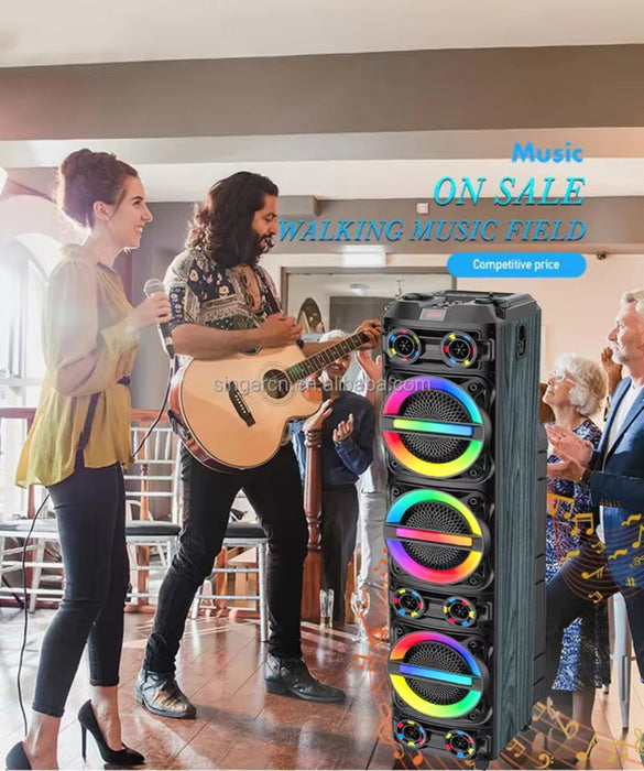 Portable music speaker with colorful lights on a stage with people playing guitar and singing.