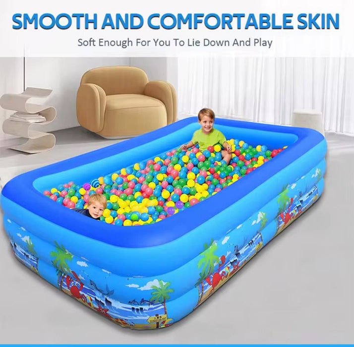 Children playing in an inflatable pool with colorful balls in a room.