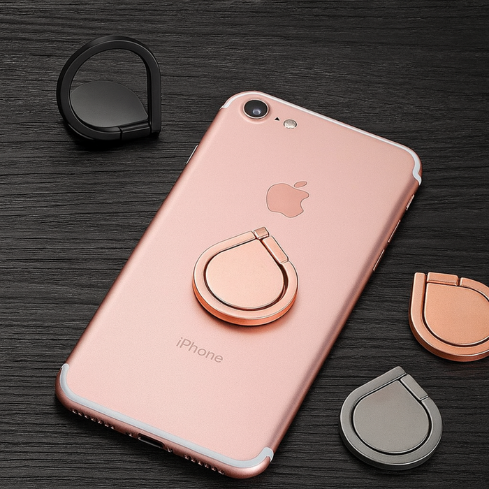 Rose gold phone case with ring holder on an iPhone, surrounded by additional ring holders on a dark surface.