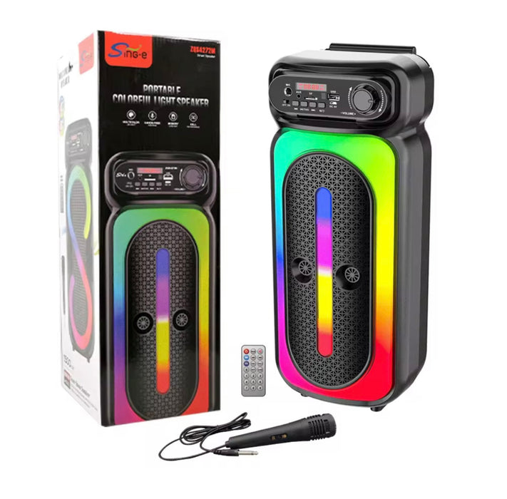 Portable colorable light speaker with remote control and microphone, next to its packaging.