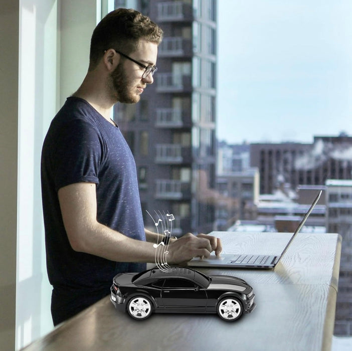 Man using a laptop with a toy car on a desk by a window with cityscape view