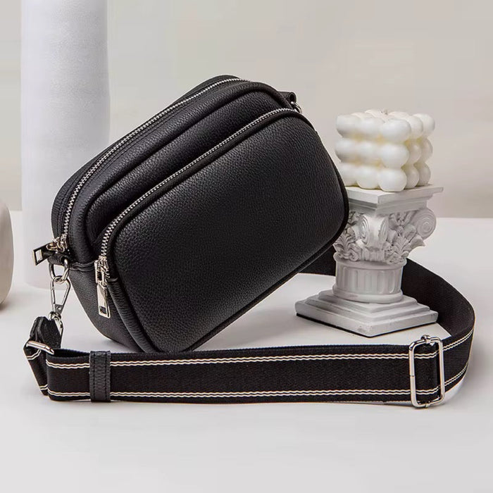 Black leather crossbody bag with a strap on a light background