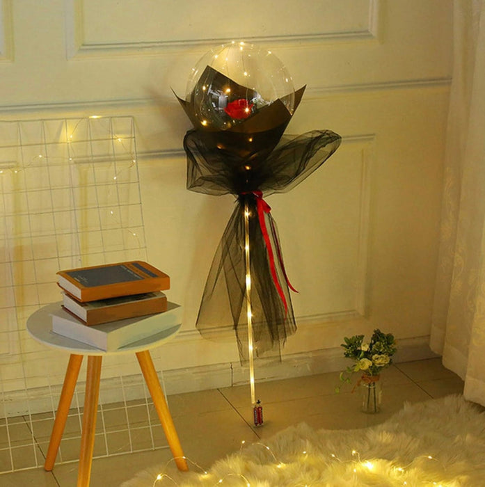 Decorative balloon with LED lights on a small round table against a neutral wall.