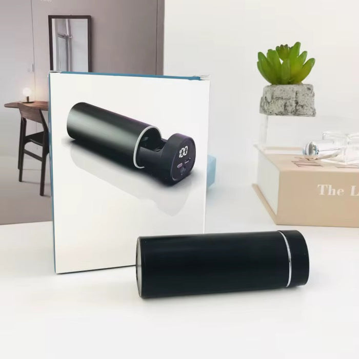 Black cylindrical device with digital display on a white surface, with a mirror reflecting the device.