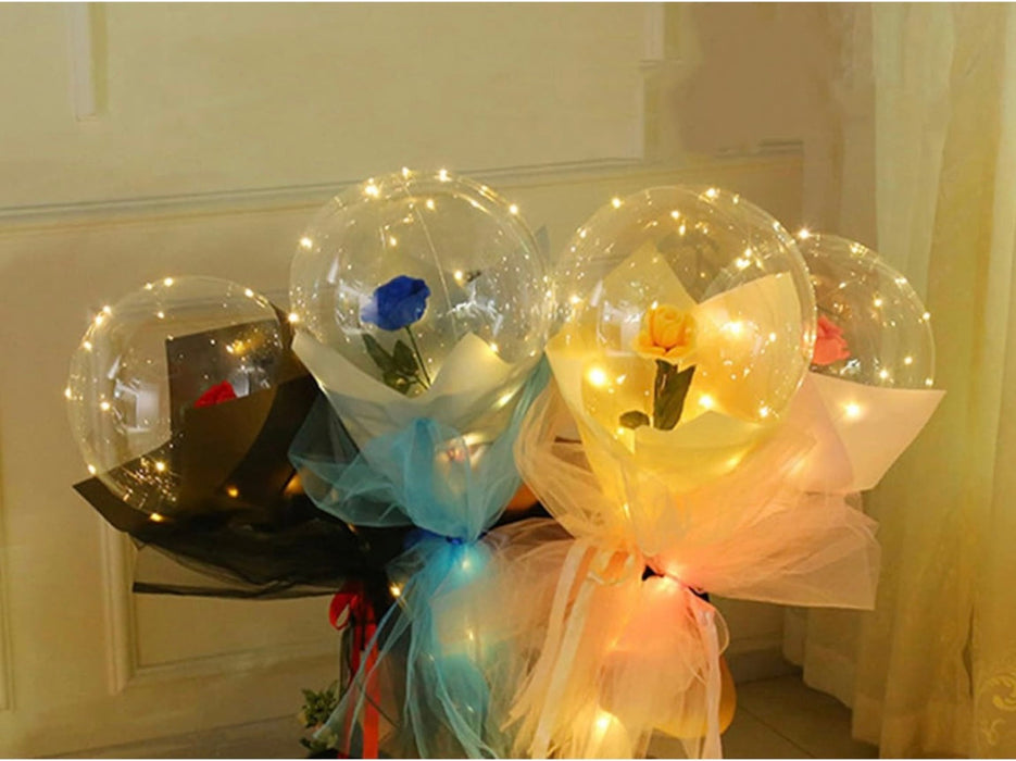 Bouquets of flowers in transparent balloons with LED lights on a white surface.
