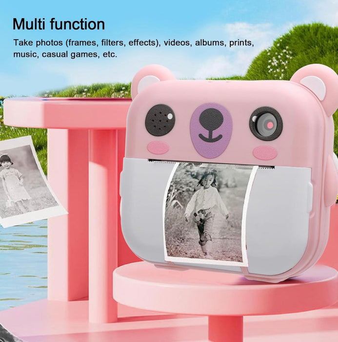 Pink bear-shaped camera with screen displaying a photo, on a pink stand with a scenic background.