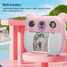 Pink bear-shaped camera with screen displaying a photo, on a pink stand with a scenic background.