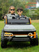 Two children in a toy electric off-road vehicle on grass with text about the vehicle's features.