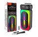 Portable colorable light speaker with remote control and microphone, next to its packaging.