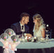 Couple sharing a romantic dinner at night with candles and flowers.