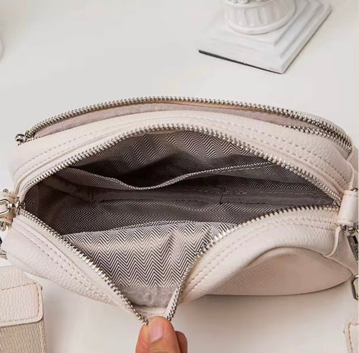Close-up of a beige handbag with a zipper, showing the interior.