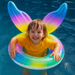 Child in a pool with a rainbow inflatable ring and colorful ears.